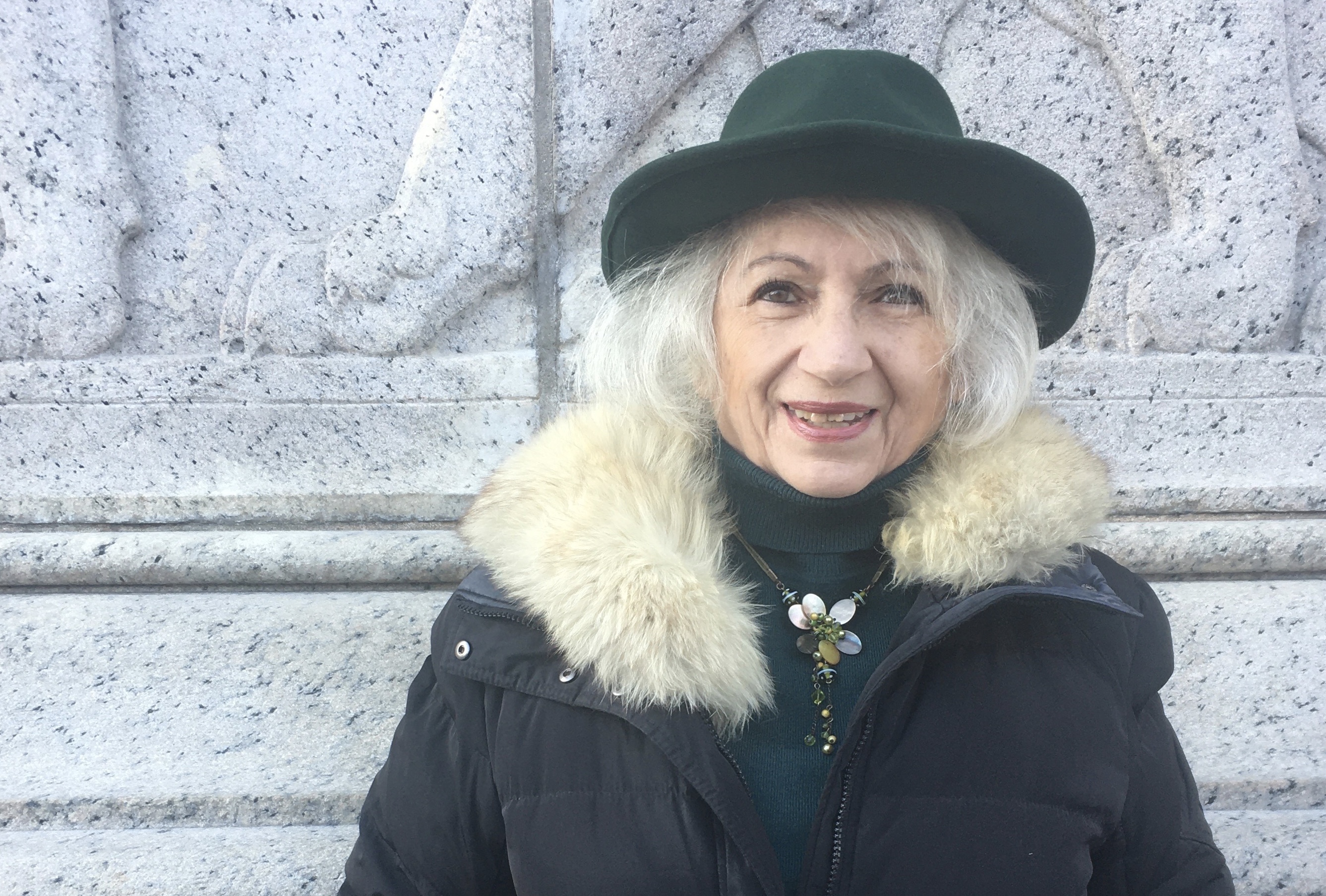 Anna Frajlich smiling, wearing a green hat and fur-trimmed coat